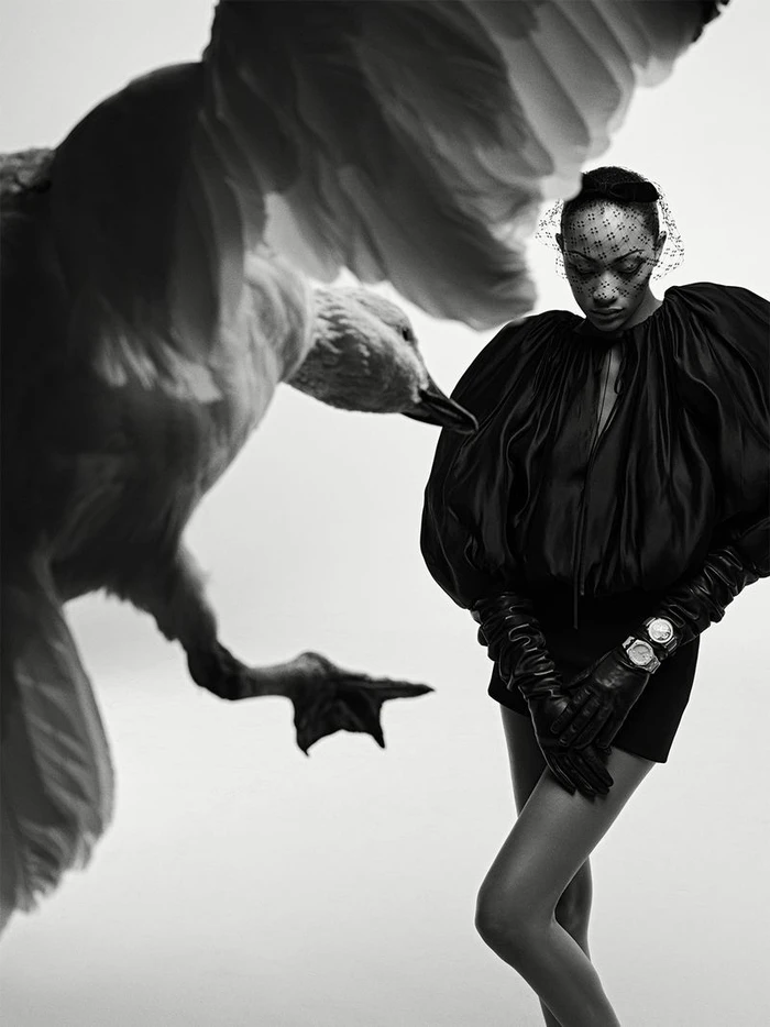 Model Selena Forrest wearing a black outfit with dramatic sleeves and leather gloves alongside a large goose.