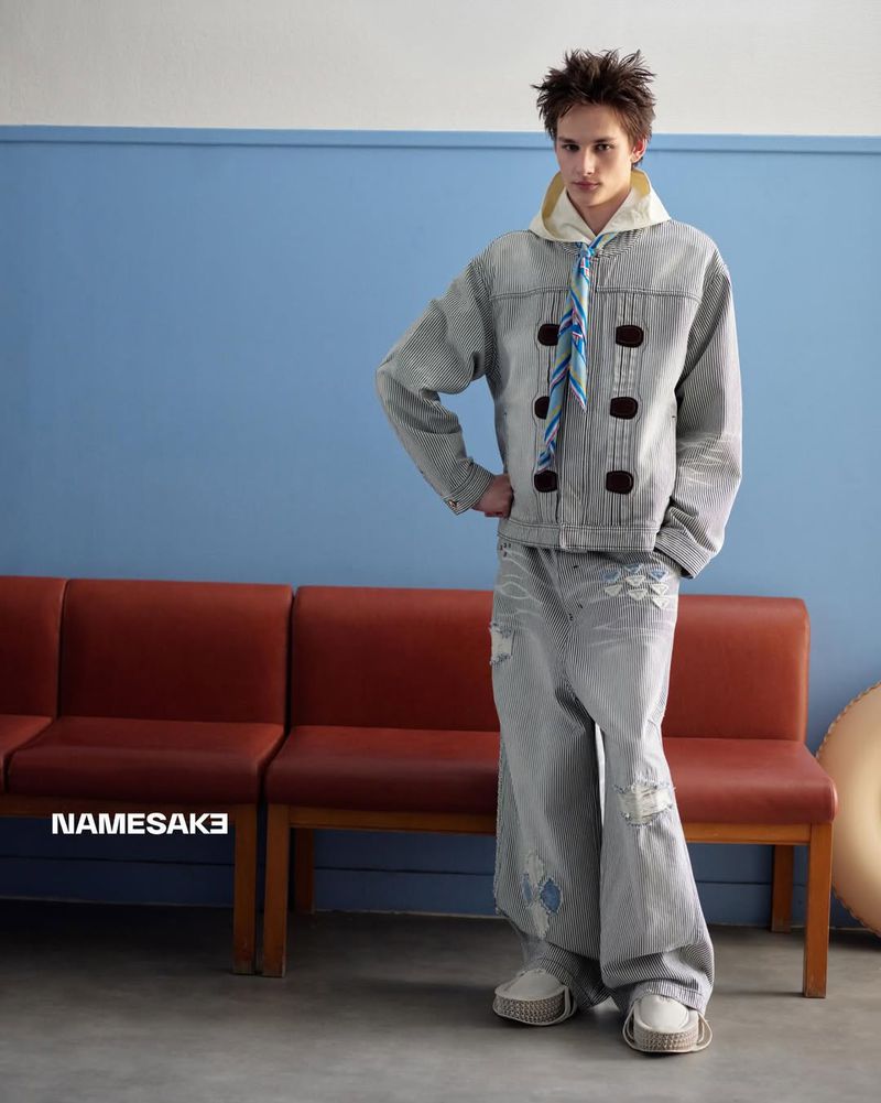 Model standing in a grey matching set with distressed wide-leg jeans in front of a red bench and blue wall.
