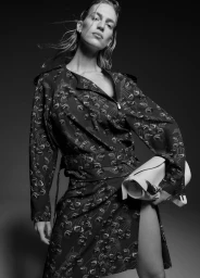 Model in printed patterned coat holding a white handbag against dark studio background for Harper's Bazaar Australia