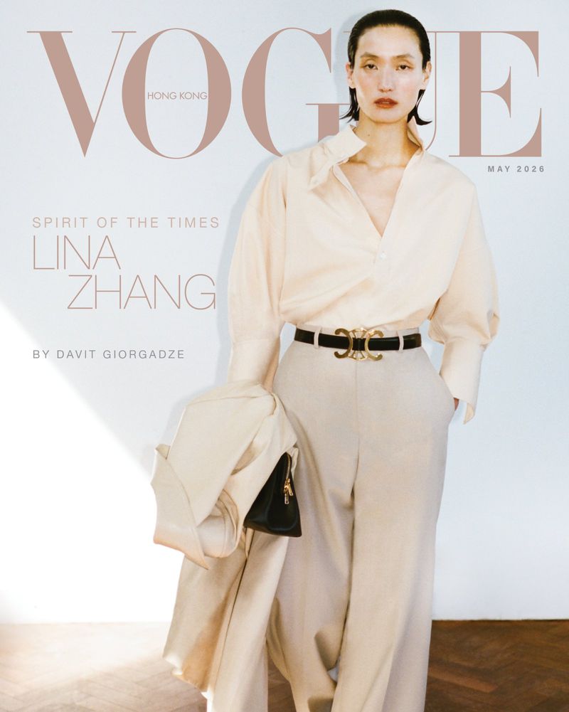 Model Lina Zhang wearing a cream blouse and trousers holding a jacket against a plain background