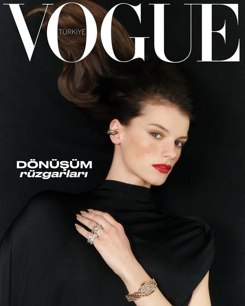 Model in black top wearing rings and a watch against a dark background for Vogue Turkey cover