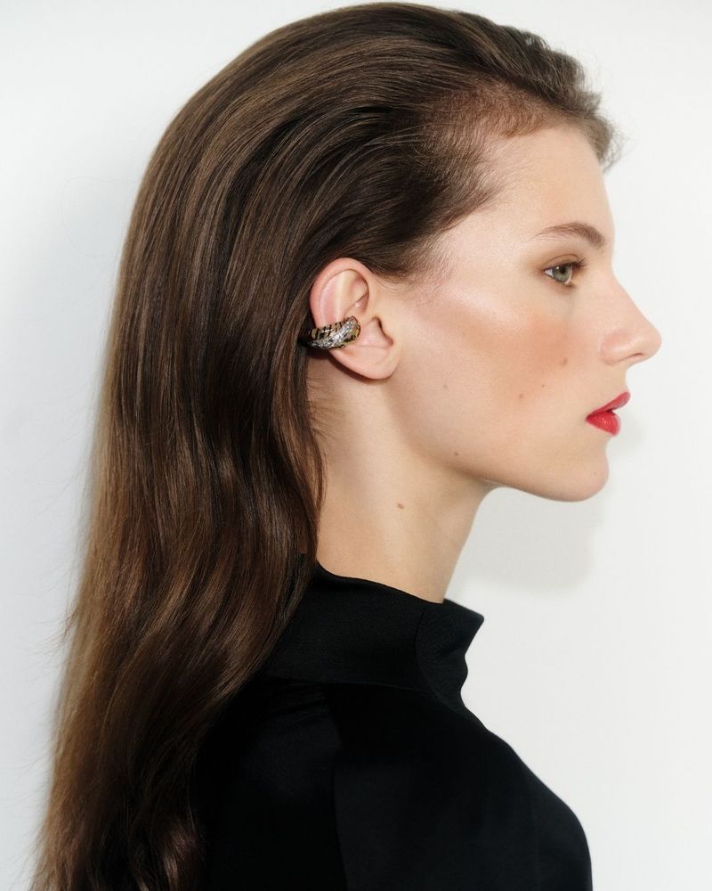 Profile portrait of a woman wearing a dark top and an ear cuff against a plain white background for Vogue Turkey May 2026 Covers.