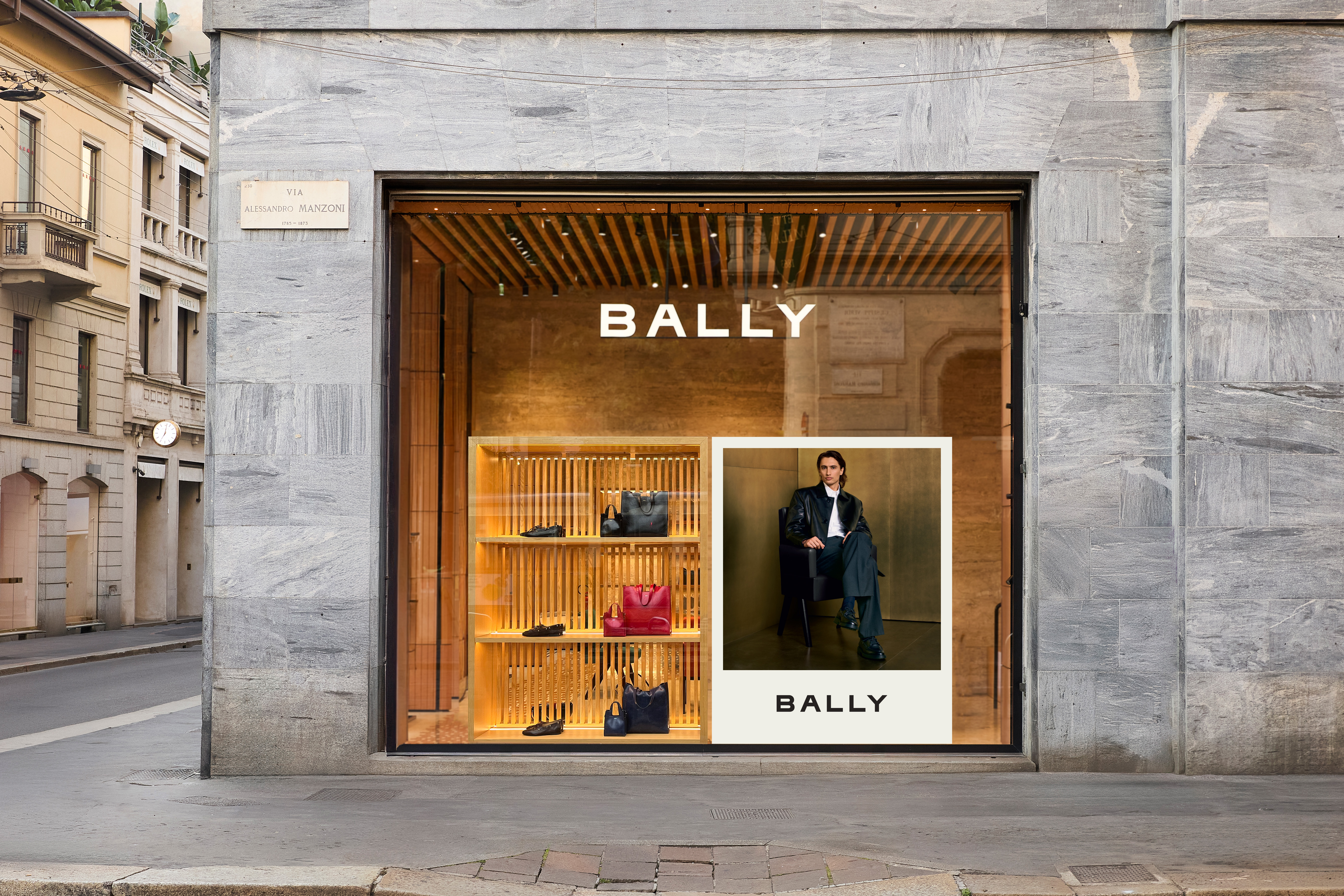Bally retail store window display on a street featuring shelves with bags and an ad campaign poster