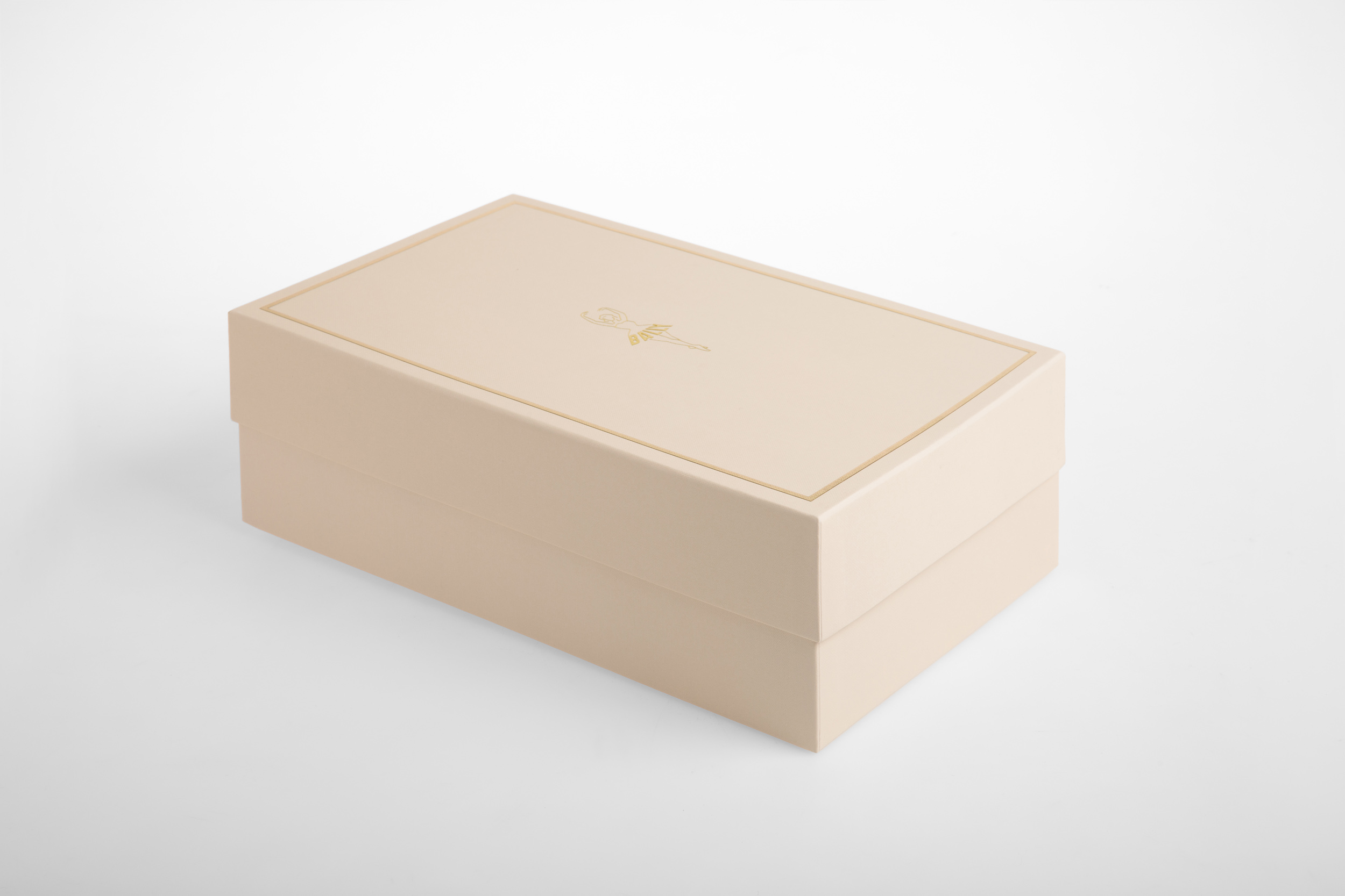 Beige rectangular gift box with gold accents and a lid is centered in a studio shot against a bright white background.