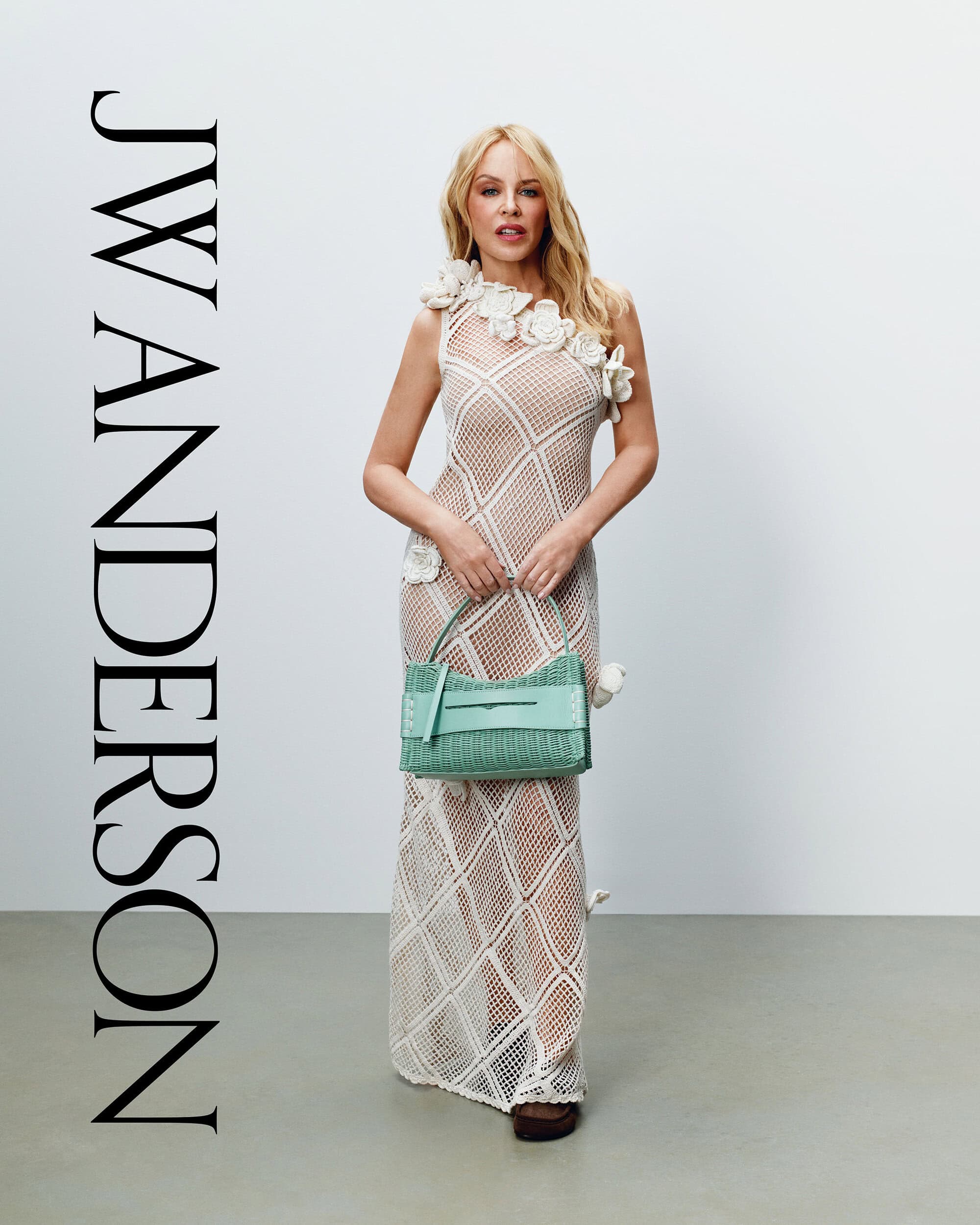 Kylie Minogue wearing an open-work crochet dress and holding a green handbag for J.W. Anderson Fall 2026
