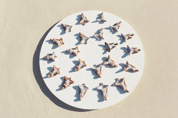 Overhead shot showcases a circular arrangement of miniature human figures in various yoga poses on a white surface against a cream-colored backdrop.