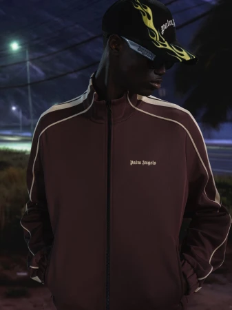 Model in brown track jacket and flame cap for Palm Angels Island Speed campaign