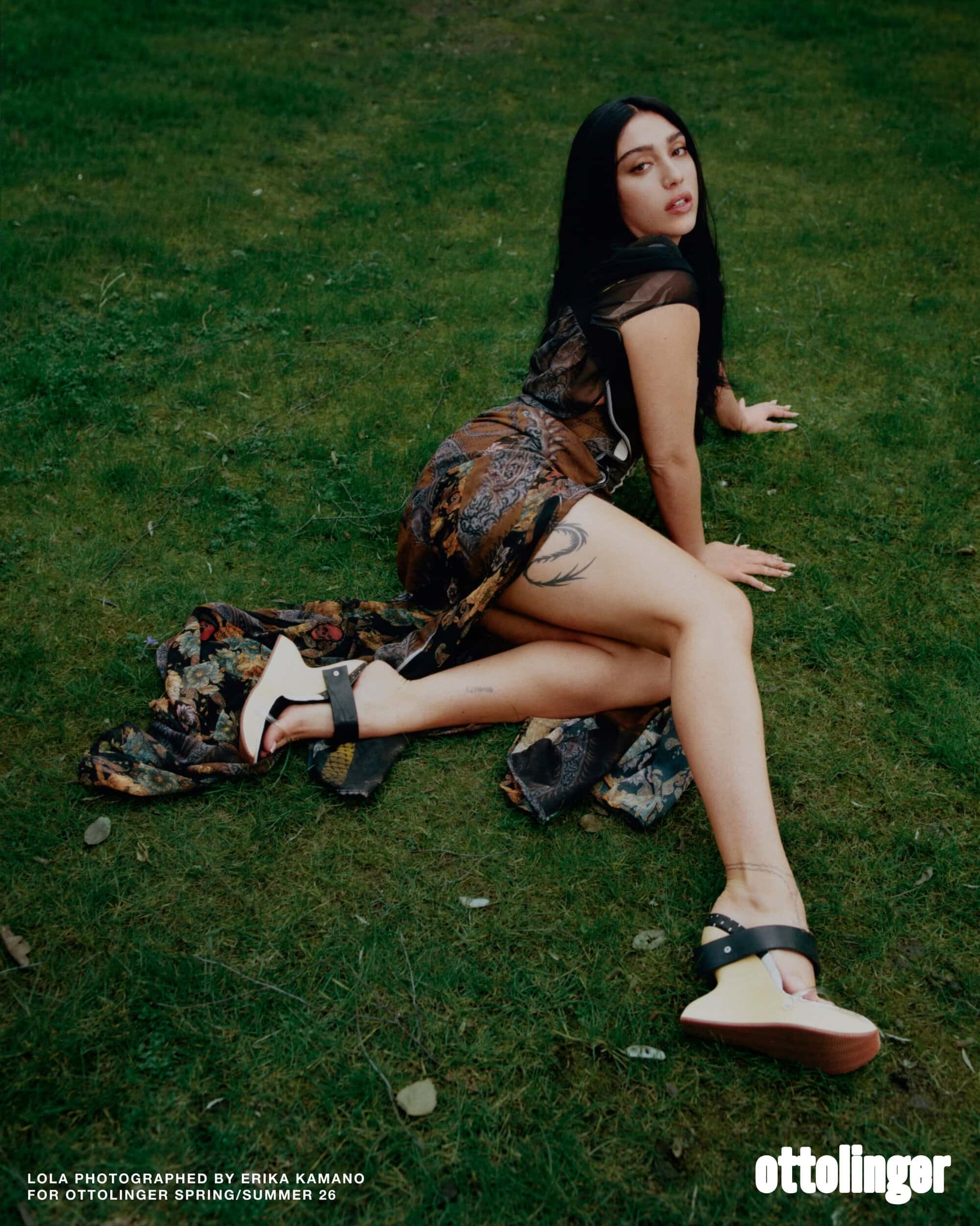 Model Lola Leon wearing printed dress and wedge shoes kneeling on grass for Ottolinger ad campaign