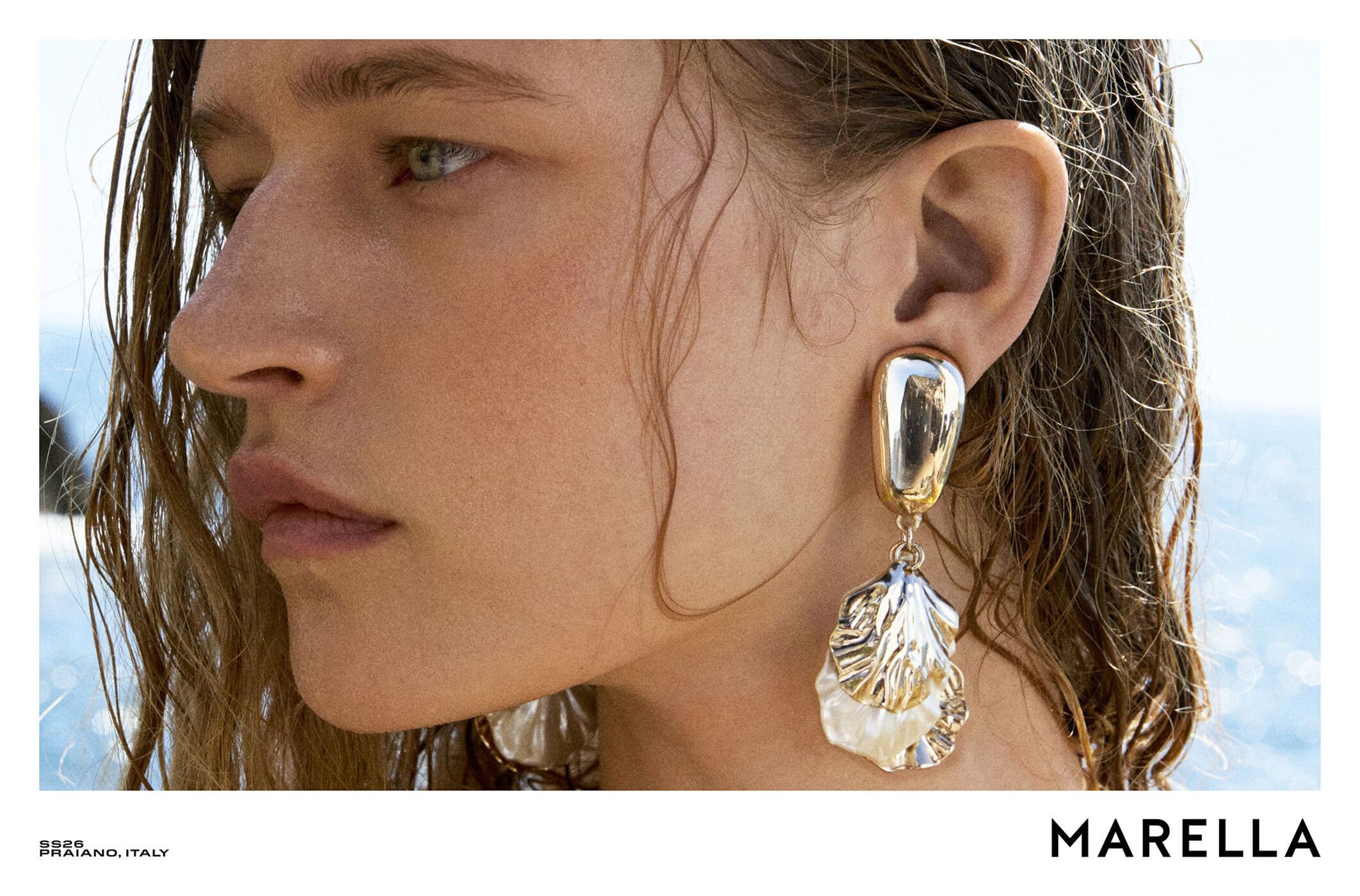Close-up portrait of a woman with wet hair wearing a metallic drop earring for Marella campaign
