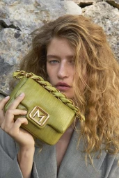Model holding a green leather handbag against a rocky background for the Marella summer 2026 campaign.