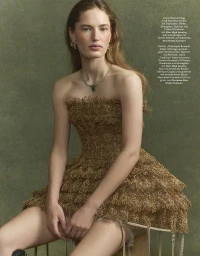 Model in a textured gold strapless dress wearing a gemstone necklace against a green background