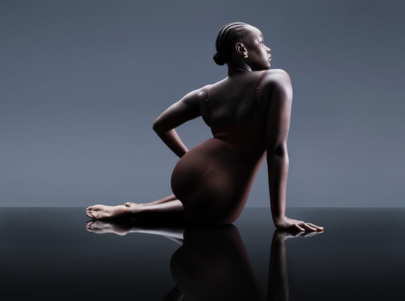 Model Ajok Daing seated on a reflective surface wearing a brown bodysuit for Marks and Spencer photographed by Gus and Lo