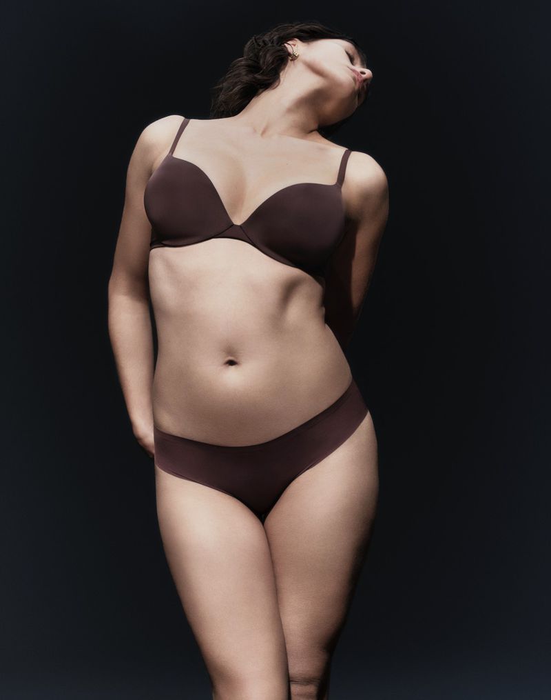 Model wearing dark brown lingerie set posing against a dark background, photographed by Gus and Lo for Marks and Spencer