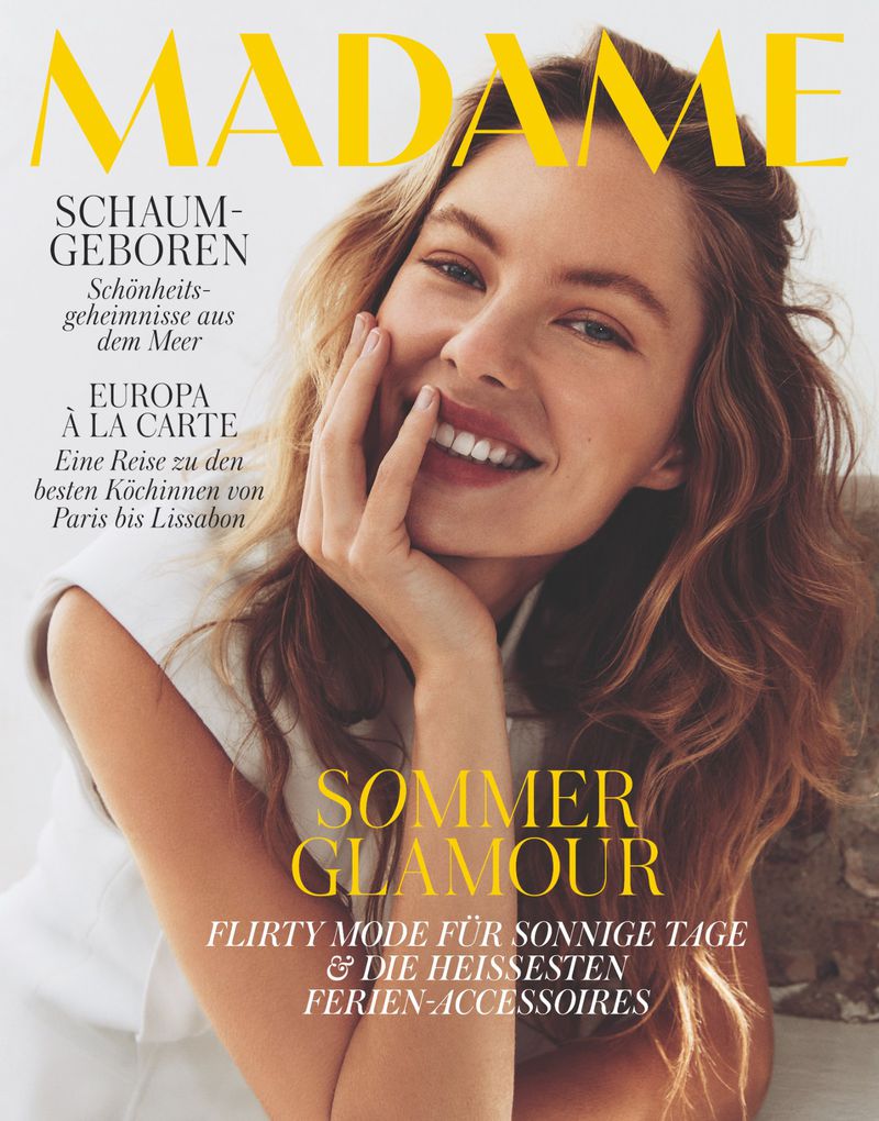 Magazine cover featuring a smiling woman with light brown wavy hair, fair skin, and natural makeup, promoting beauty and fashion.
