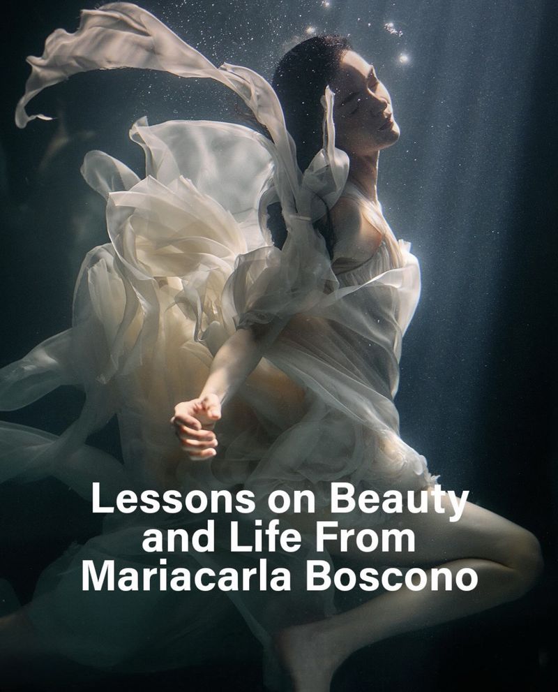 Model Mariacarla Boscono floating underwater wearing a flowing white sheer dress with dramatic lighting.