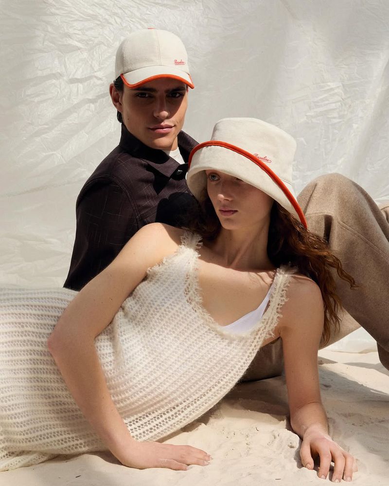 Two models wearing white hats by Borsalino pose together against a wrinkled white paper backdrop for the SS2026 campaign.