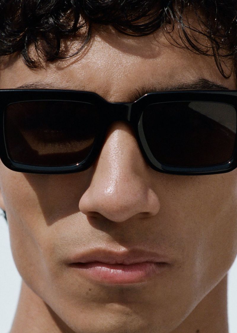 Close-up portrait of a man wearing black sunglasses against a bright background for Samsøe Samsøe Pre Autumn 26.