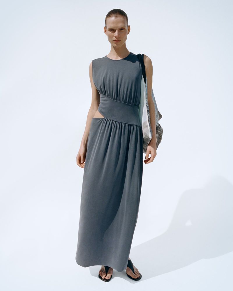 Model wearing a grey sleeveless maxi dress with side cutouts against a white seamless background