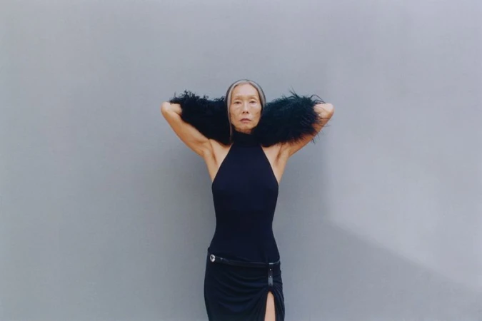 Model Yuri Fukuhara in black halter dress with fur stole against a grey background for Puss Puss Magazine