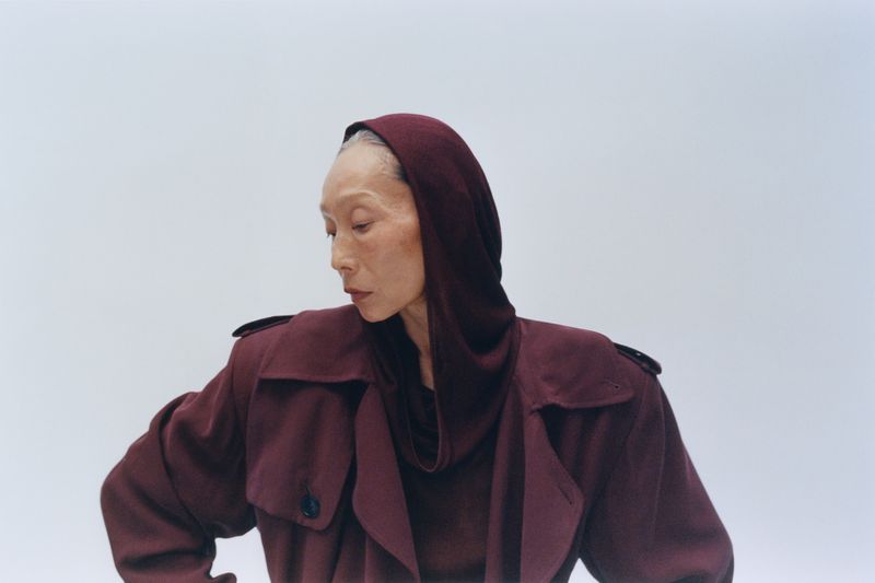 Model wearing a deep burgundy hooded coat against a plain white background for Puss Puss Magazine
