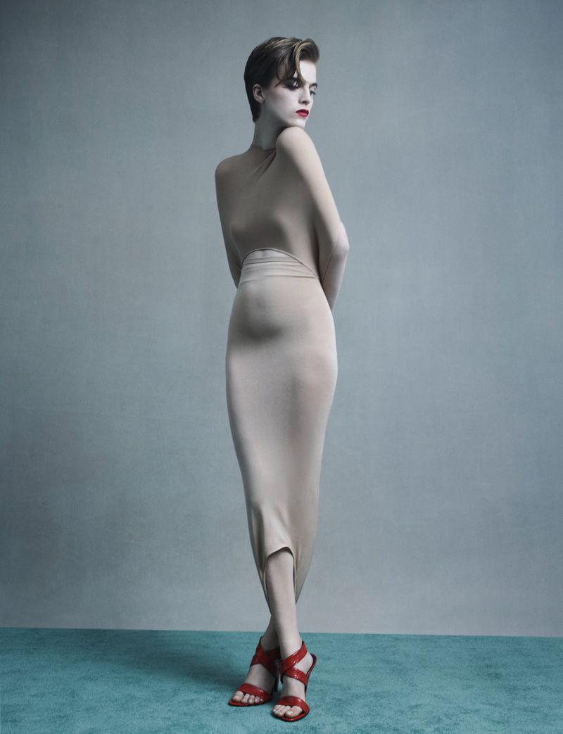 Model Libby in a nude fitted dress and red heels posing against a grey studio backdrop for Re-Edition Magazine