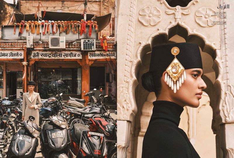 Editorial fashion shot: Woman in black turtleneck, ornate headpiece, and earrings. Background shows urban Indian street scene with motorbikes.