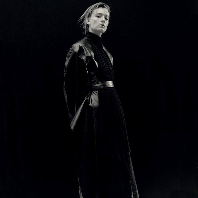 Monochrome portrait of a model wearing a dark leather coat against a black background shot by Kito Munoz for Re-Edition Magazine.