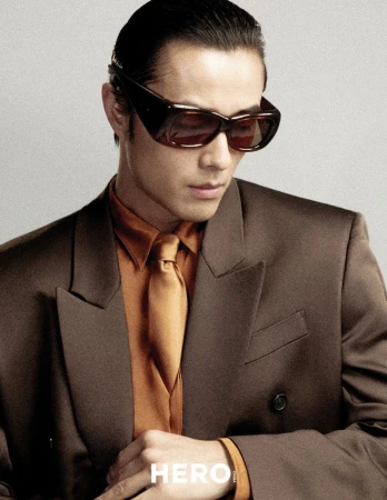 Model Zhao Lei wearing dark sunglasses, brown suit jacket, and orange shirt for Hero China by photographer Shenyun Ren.