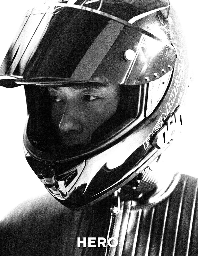 Close-up portrait of model Zhao Lei wearing a black motorcycle helmet and leather jacket against a bright background