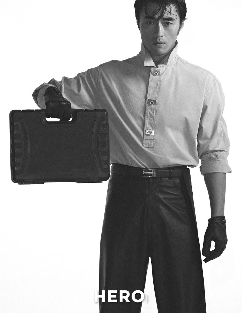 Asian man in high collar shirt holding a dark briefcase against a white seamless background