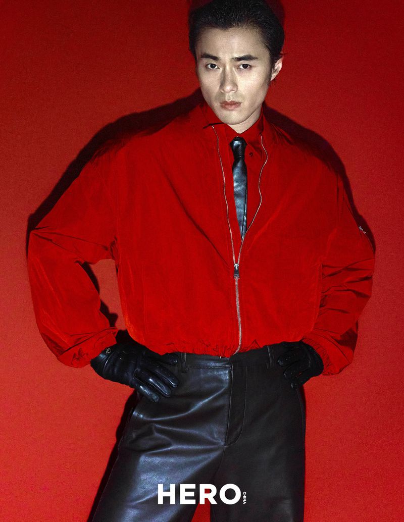 Model Zhao Lei wearing a red jacket and black leather trousers against a solid red background for Hero China.