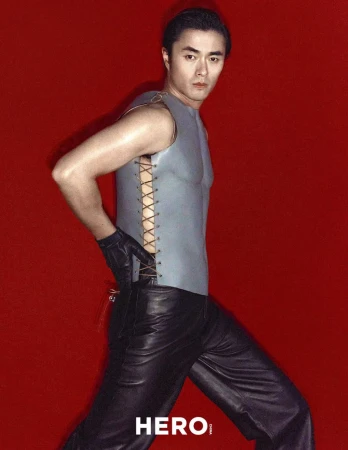 Model Zhao Lei wearing a grey sleeveless top and black leather pants against a vibrant red background for Hero China