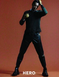 Model Zhao Lei wearing a dark knit sweater and leather pants with yellow gloves against a warm background.