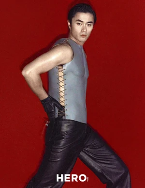 Model Zhao Lei wearing a grey sleeveless top and black leather pants against a vibrant red background for Hero China
