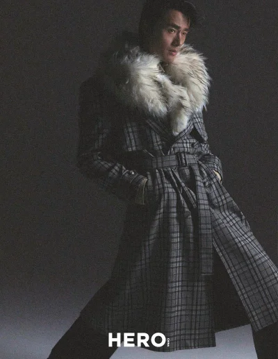 Model Zhao Lei wearing a belted plaid coat with a faux fur collar in a studio editorial for Hero China photographed by Shenyun Ren.