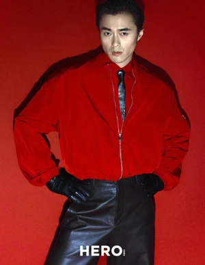 Model Zhao Lei wearing a red jacket and black leather trousers against a solid red background for Hero China.