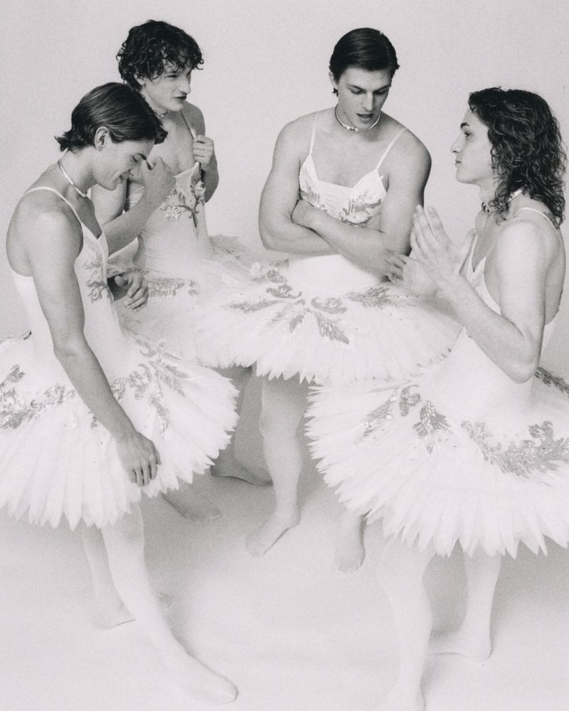 Four male dancers wearing white tutus and tights posed together in a studio setting for ODDA Magazine