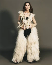 Brooke Shields wearing a feathered top and fringed chaps against a grey studio backdrop for ODDA Magazine