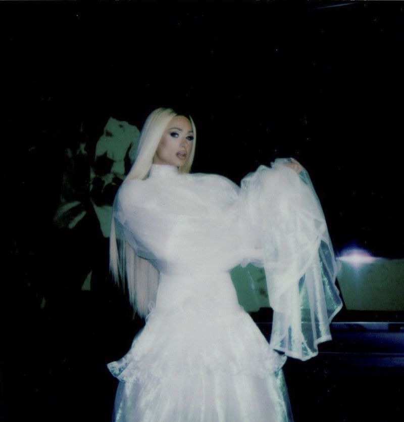 Paris Hilton wearing a white gown with sheer puffed sleeves against a dark background for ODDA Magazine