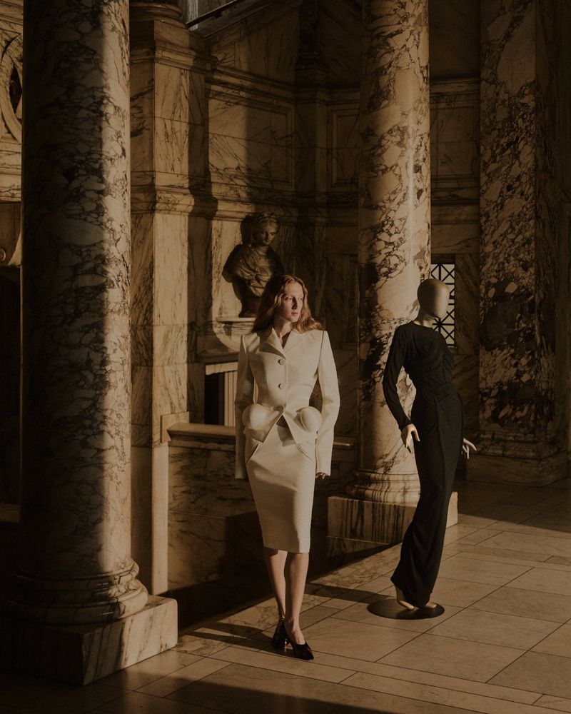 Model standing next to a black mannequin in a classical hall with marble columns for Telegraph Luxury by Daniel Benson