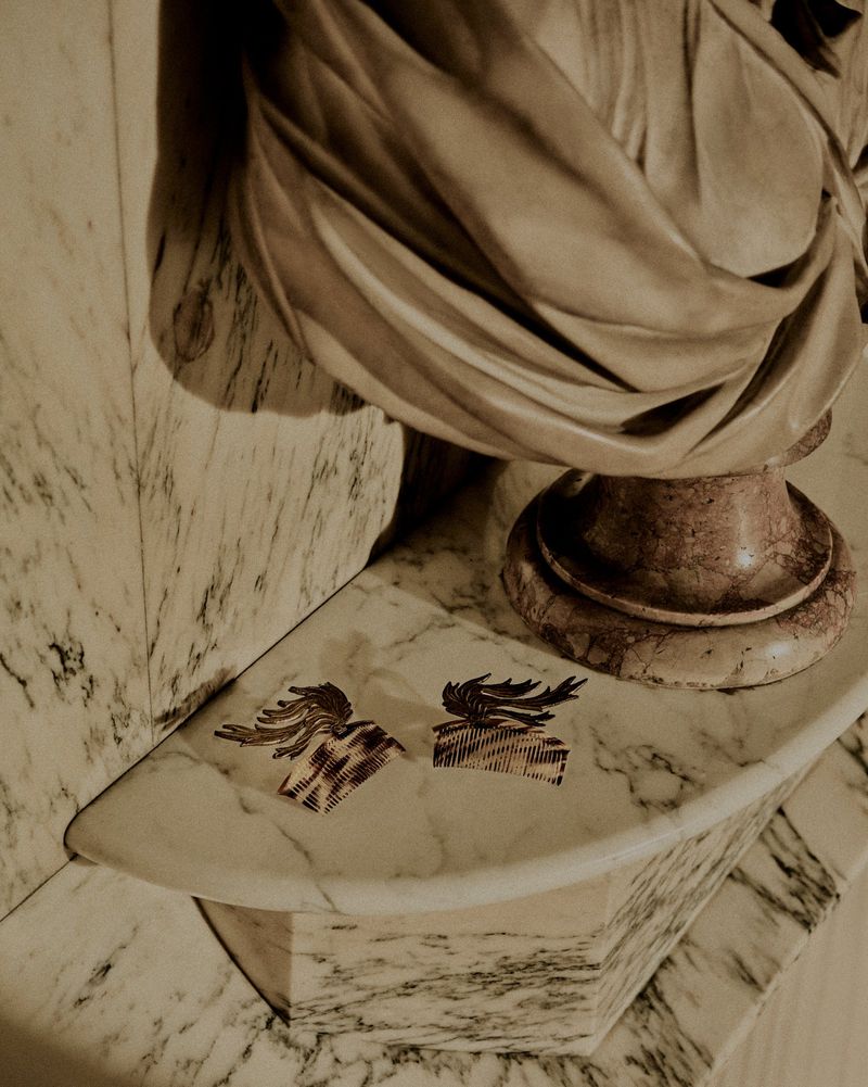 Marble bust and pedestal featuring draped sculptural fabric against a veined marble surface with patterned attachments