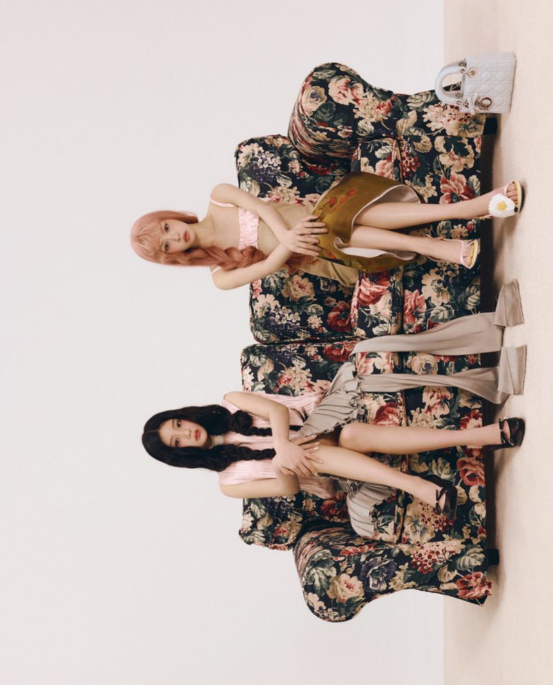 Two female models posing on a vintage floral armchair against a plain studio background for ODDA Magazine