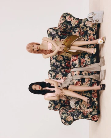 Two female models posing on a vintage floral armchair against a plain studio background for ODDA Magazine