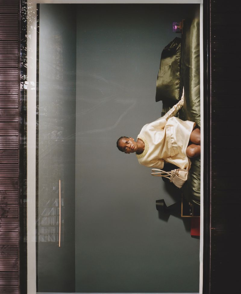 Letitia Wright sitting on a green satin bed in an editorial portrait for ODDA Magazine.