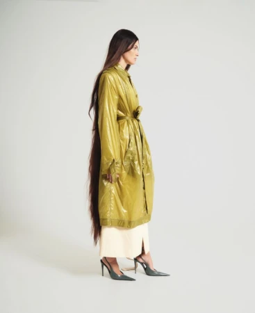 Isabeli Fontana in a shiny olive green coat with very long dark hair against a plain white background for ODDA Magazine.