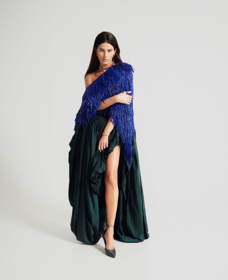 Model Isabeli Fontana wearing a blue fringed top and dark skirt against a white studio background for ODDA Magazine