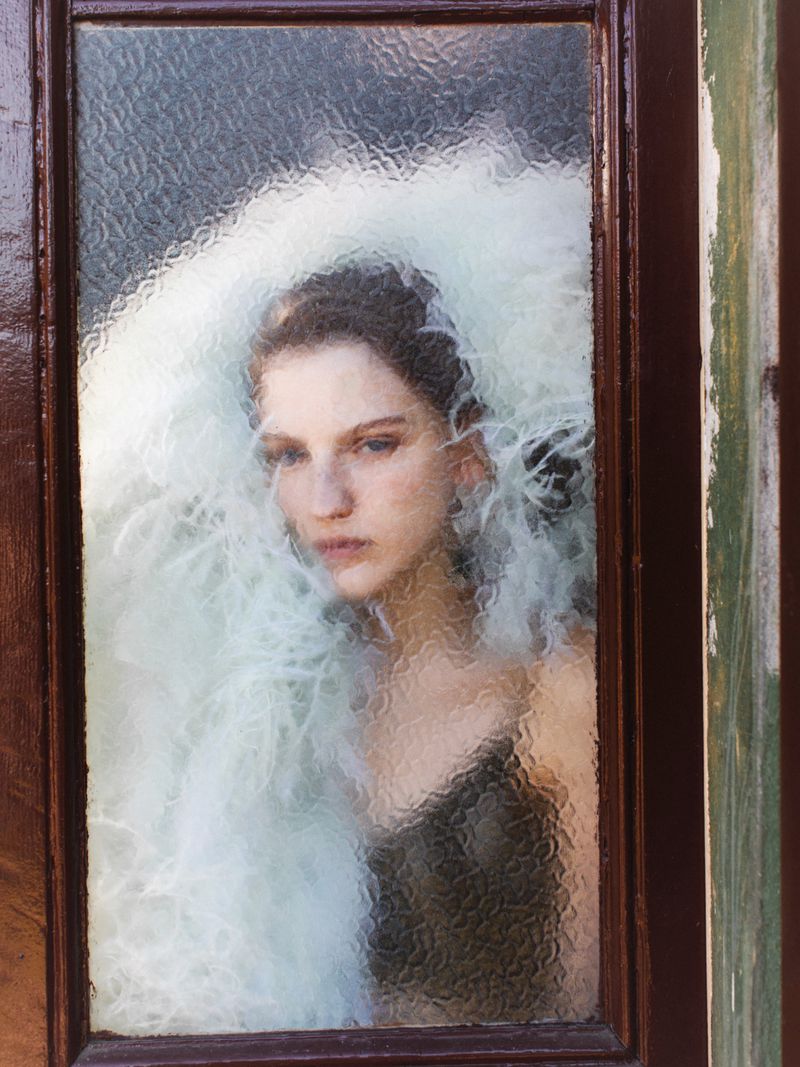 Model viewed through textured patterned glass framed by dark wood door frame for ODDA Magazine editorial project