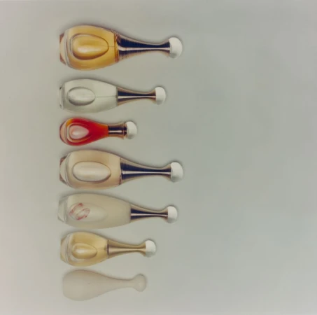 Seven perfume bottles arranged vertically on a pale background from The Majestic Aphrodite project for ODDA Magazine.