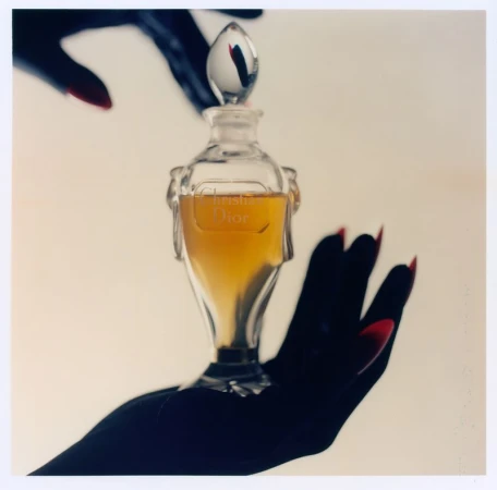 Crystal perfume bottle held in black-gloved hands against a neutral background for ODDA Magazine