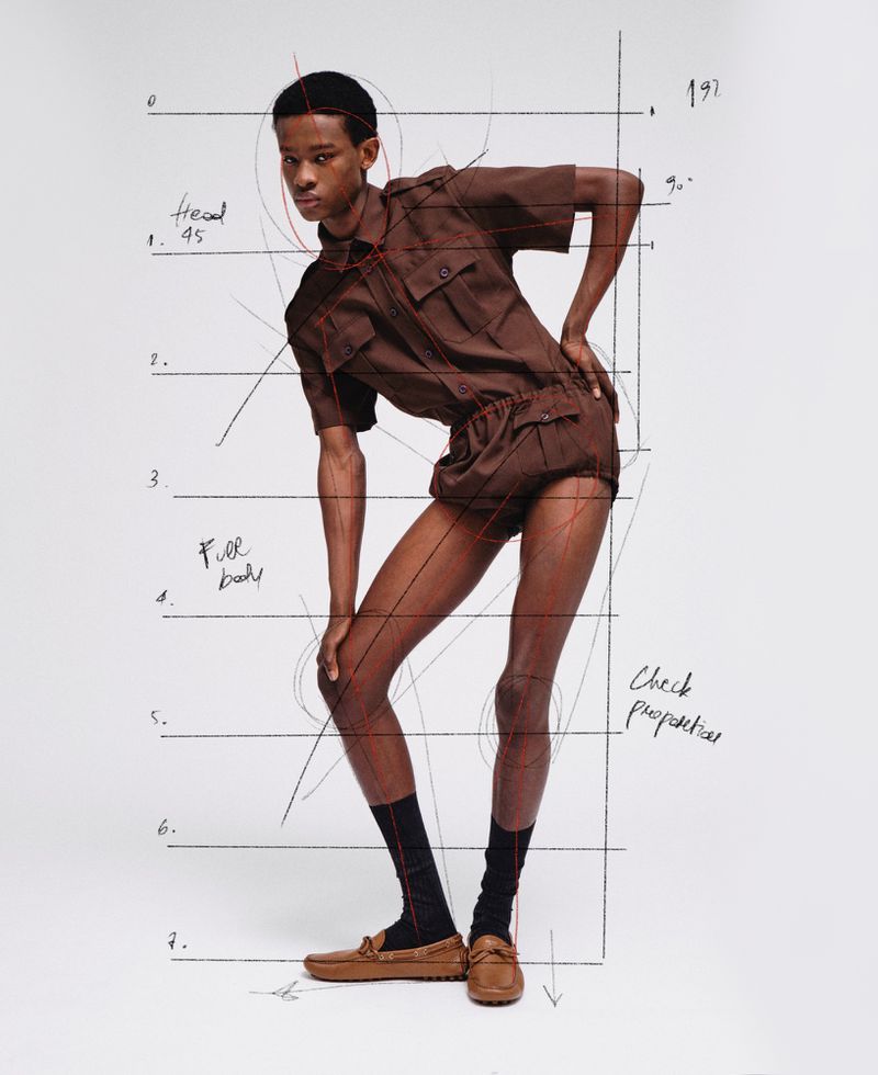 Model in brown short-sleeve shirt and shorts with hand-drawn anatomical diagram lines overlaying the white background.